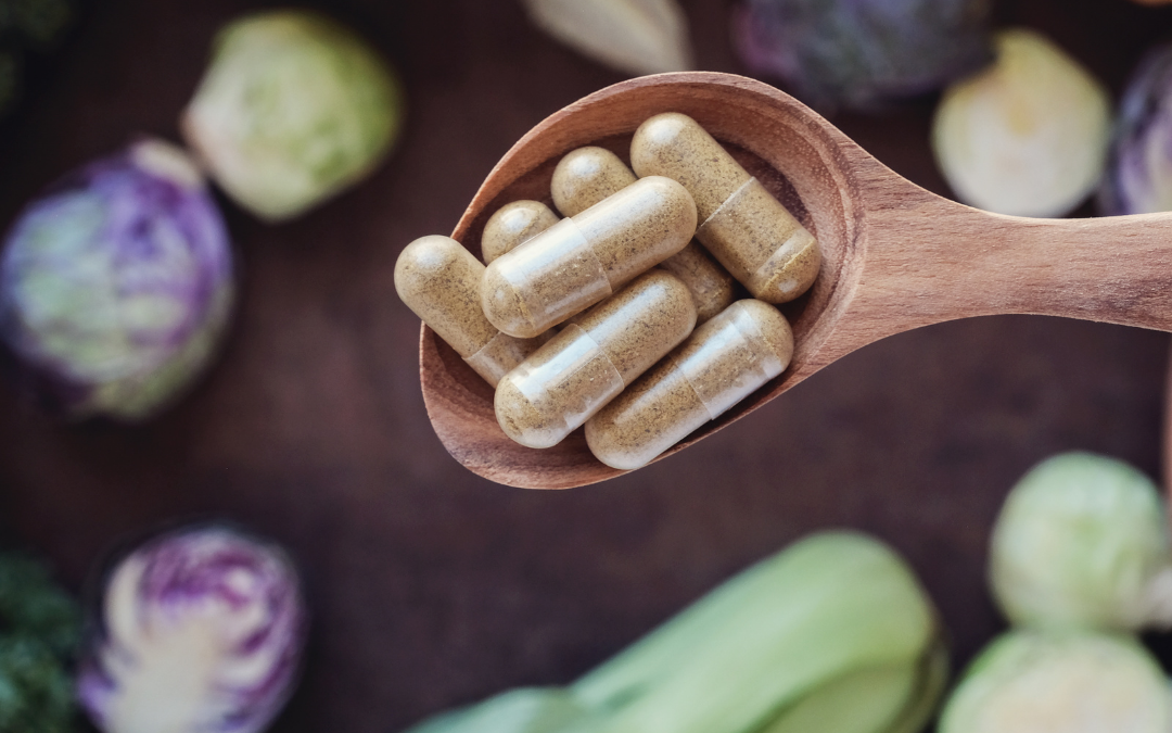 supplements on a wooden spoon surrounded by natural ingredients